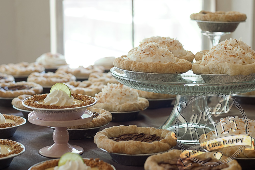 A pie buffet with many different types of mini pies arranged on serving pedastals