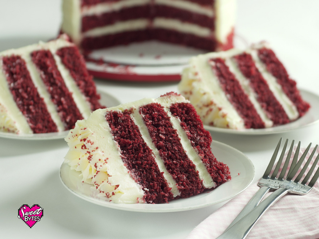 slices of red velvet cake with the whole red velvet layered cake in the background