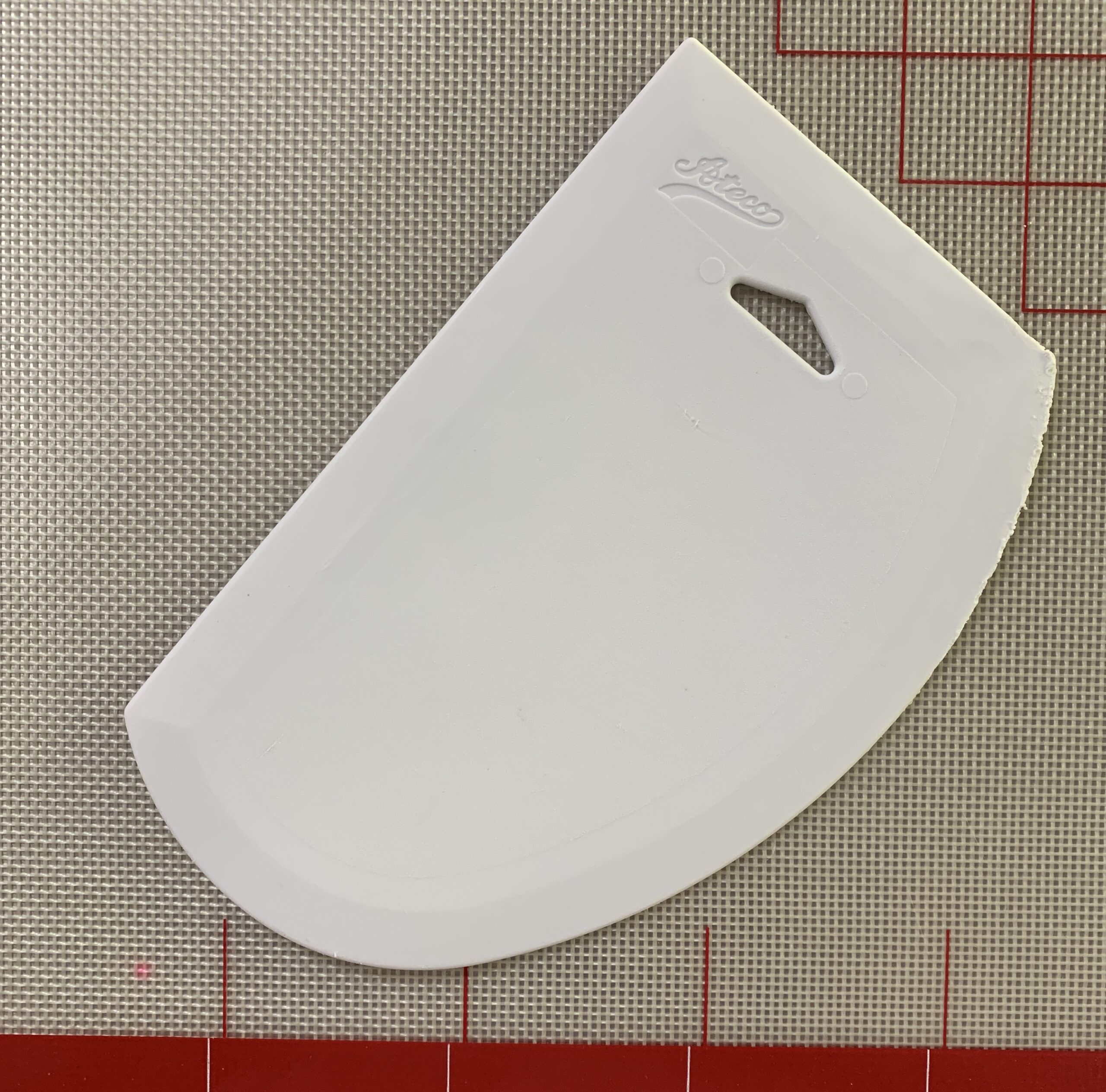 a white plastic bowl scraper on a silicone mat