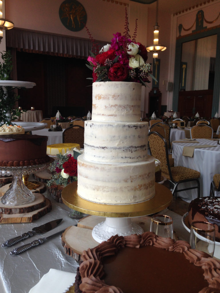 Three tiered semi-naked wedding cake with real flowers on top