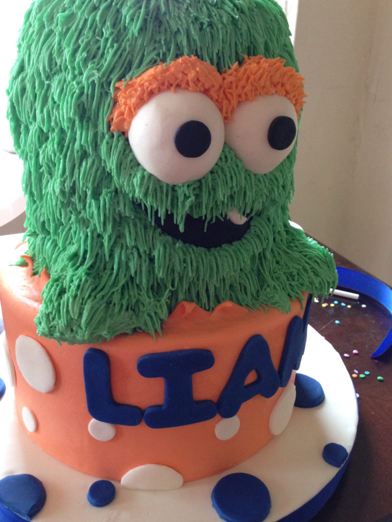 Green monster cake on top of a orange, polka dot bottom layer cake