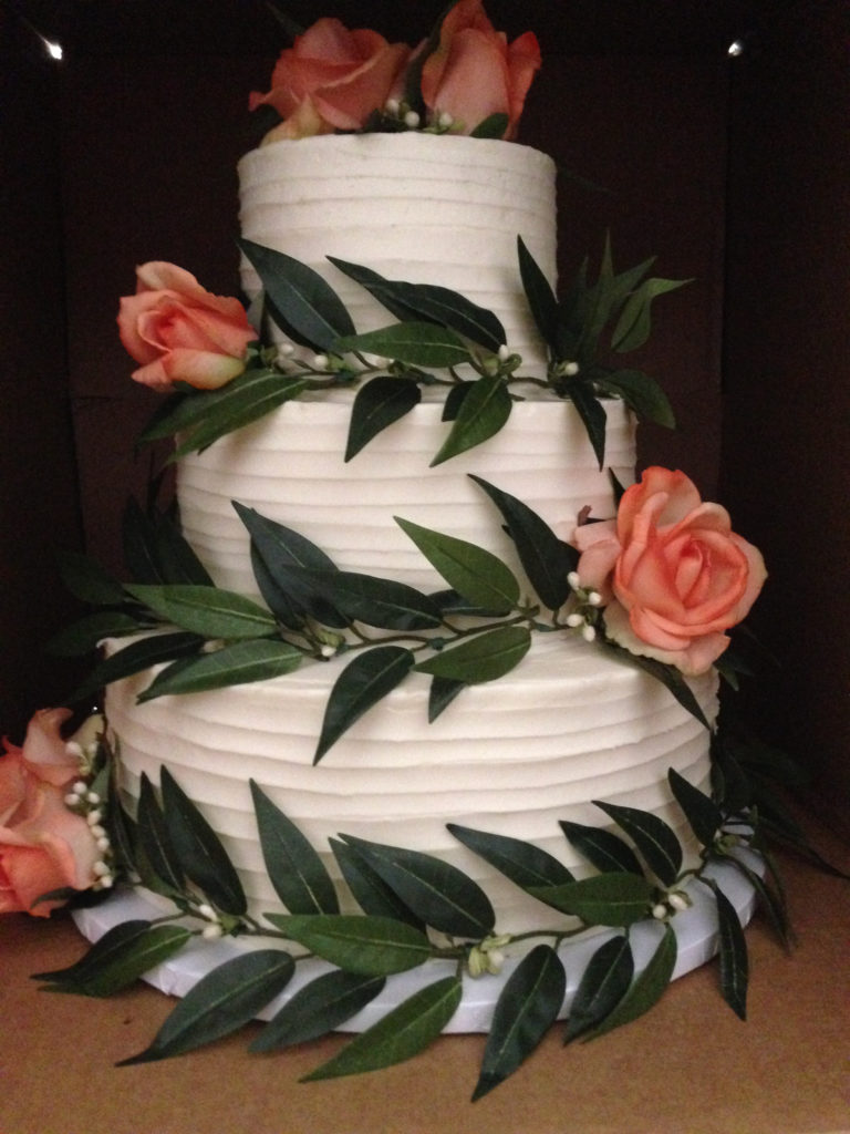 three tiered wedding cake with peach roses and a spatula texture