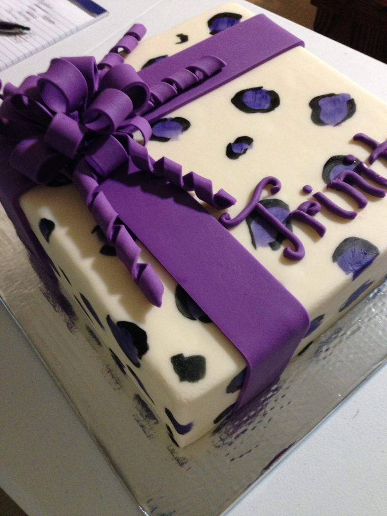 Gift box cake with purple fondant ribbon and animal spots painted on the box