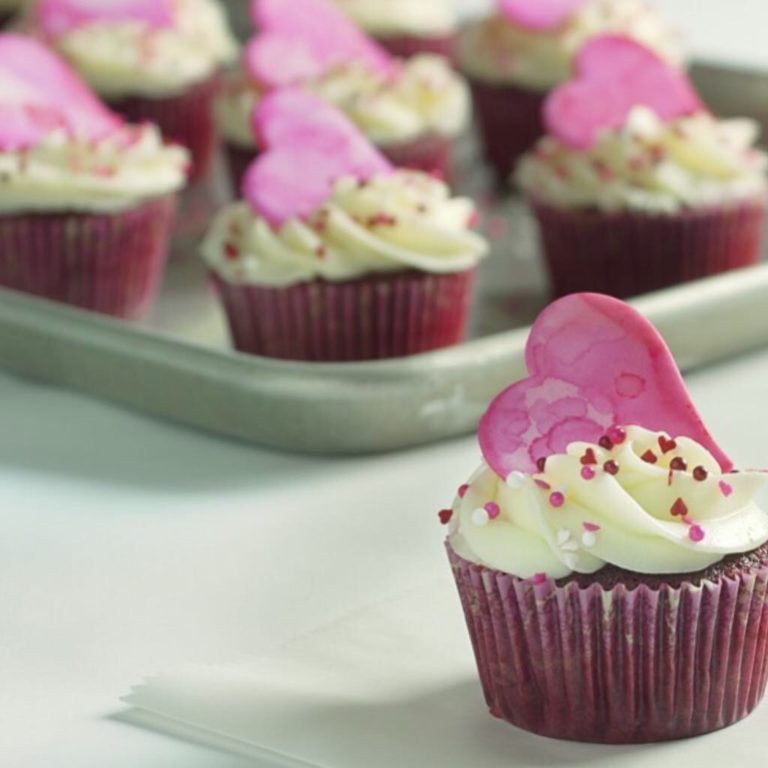 A decorated cupcake with a painted heart made of fondant on top.